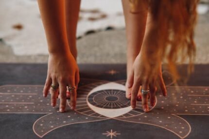 Detailed view of hands with rings in yoga pose on a decorative mat.